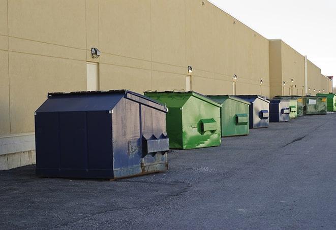 a forklift lifts a full dumpster from a work area in Champion